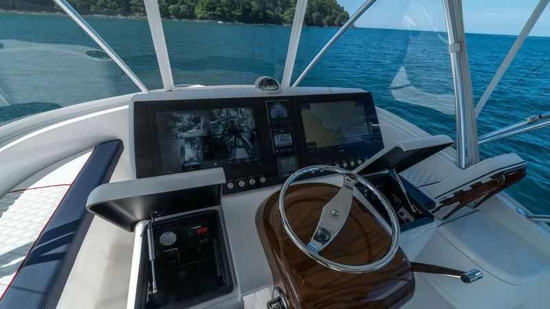 Slide: The Image of Helm Station with Panoramic View The helm station on the Viking 46 BF offers a commanding view of the surrounding waters, accentuated by sleek, modern instrumentation. The polished wood finish of the steering console adds elegance, complemented by state-of-the-art navigation displays. Ex - 7854769