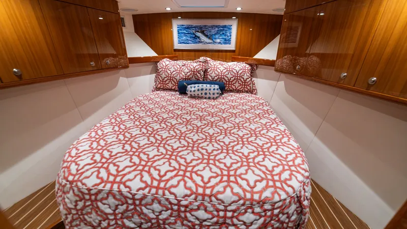 Slide: The Image of Forward Stateroom with Double Berth The forward stateroom on the Viking 46 BF features a spacious double berth adorned with a patterned comforter, creating a welcoming and stylish atmosphere. Rich wood cabinetry provides ample storage, while the overhead skylight and recessed lighting enhan - 7854756