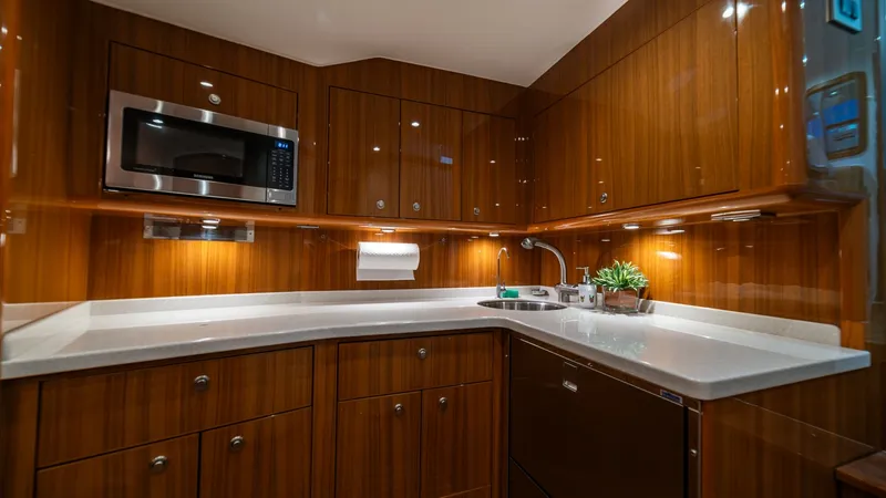 Slide: The Image of Galley with Modern Amenities This well-appointed galley on the Viking 46 BF features sleek, high-gloss wood cabinetry and state-of-the-art appliances, including a built-in microwave. The solid surface countertops provide ample preparation space, while under-cabinet lighting enhances - 7854752