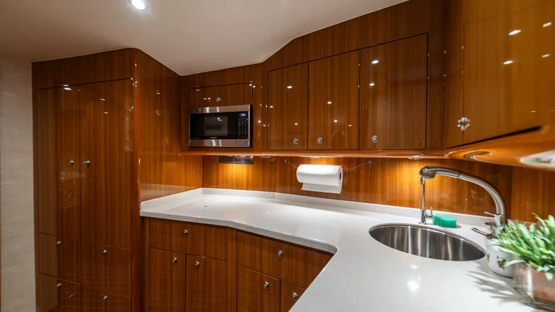 Slide: The Image of Elegant Galley with Modern Amenities The galley of the Viking 46 BF features sleek, high-gloss wood cabinetry and modern appliances, including a built-in microwave. The expansive countertop provides ample space for meal preparation, enhanced by under-cabinet lighting that adds warmth and ele - 7854741