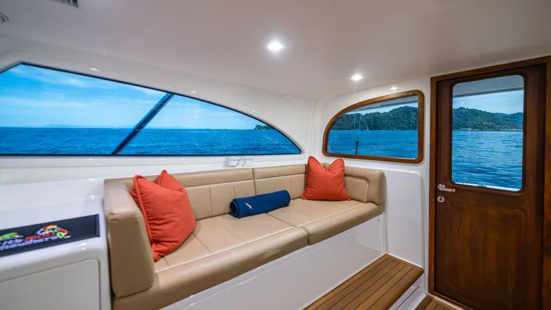 Slide: The Image of Starboard Lounge Area with Ocean View This inviting starboard lounge area on the 2020 Viking 46 BF features plush tan seating accented with vibrant pillows. Large windows provide a panoramic ocean view, enhancing the open and airy ambiance. The rich wooden door and teak flooring add a touch o - 7854748