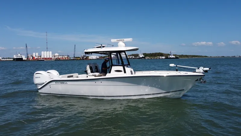 Slide: The Image of Cobia 280 Center Console Side View The 2023 Cobia 280 Center Console is showcased in this side view, highlighting its sleek and modern design. Equipped with twin Yamaha outboard engines, this vessel promises powerful performance on the water. The spacious deck and ergonomic helm station ar - 7927762