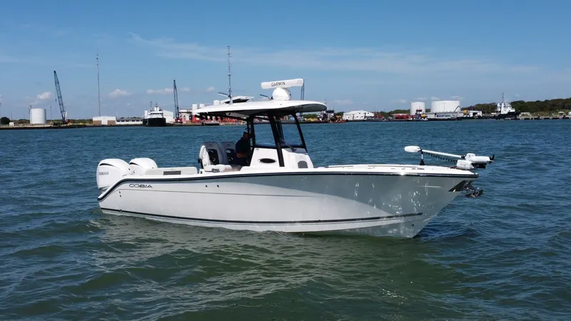 Slide: The Image of Cobia 280 Center Console Exterior The 2023 Cobia 280 Center Console is showcased on calm waters, highlighting its sleek and modern hull design. Equipped with dual outboard engines, this vessel promises powerful performance for open-water adventures. The spacious deck layout is ideal for b - 7927763