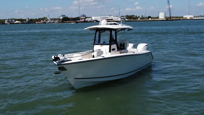 Slide: The Image of Cobia 280 Center Console Bow View The 2023 Cobia 280 Center Console is captured gracefully cutting through the water, showcasing its sleek bow design and robust hull. The spacious, open deck is perfect for both fishing and leisure, while the T-top provides ample shade. This model exemplif - 7927764
