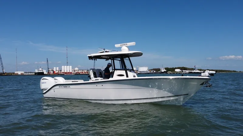 Slide: The Image of Side View of Cobia 280 Center Console This image showcases the sleek profile of the 2023 Cobia 280 Center Console, highlighting its modern design and efficient hull. The boat features a spacious deck layout with a sturdy T-top, offering ample shade and protection. Equipped with powerful twin - 7927761
