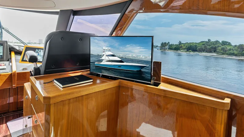 Slide: The Image of Helm Station with Scenic Views The helm station of the 2017 Viking 80 Convertible 'Aussie Rules' offers a luxurious blend of functionality and style. The polished wood finish and integrated electronics provide a sophisticated touch, while expansive windows grant panoramic views of the - 7932683