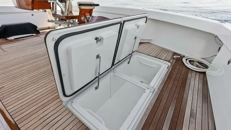 Slide: The Image of Cockpit Deck with Storage Hatch This image showcases the spacious cockpit deck of the 2017 Viking 80 Convertible, featuring a sturdy storage hatch. The teak decking adds a touch of elegance and durability, perfect for fishing or entertaining. The open hatch reveals ample storage space, - 7932698