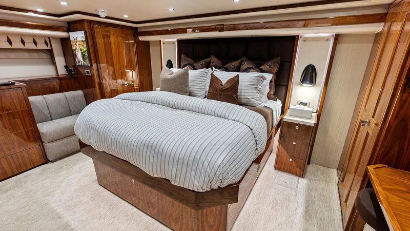 Slide: The Image of Luxurious Master Stateroom The master stateroom exudes luxury with its plush bedding and elegant wood finishes. Ambient lighting complements the soft carpet flooring, creating a warm and inviting atmosphere. Ample storage and modern bedside fixtures enhance the functionality and co - 7932663
