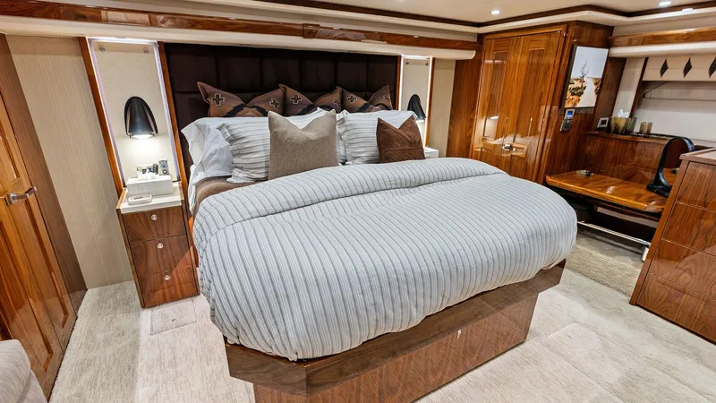 Slide: The Image of Luxurious Master Stateroom Interior The master stateroom of the 2017 Viking 80 Convertible offers a blend of elegance and comfort. Featuring a spacious king-sized bed with plush bedding, the room is accented by rich wood finishes and ample storage. Soft overhead lighting creates a warm ambi - 7932646