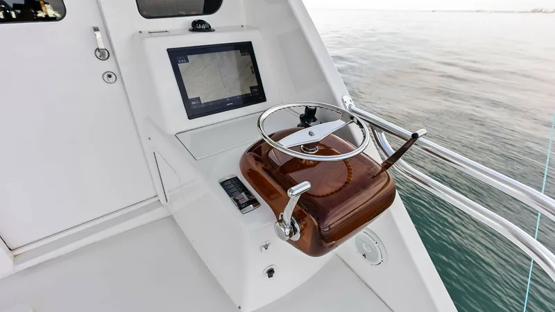Slide: The Image of Flybridge Helm Station The flybridge helm station on the 2017 Viking 80 Convertible features a sleek, modern design with a polished wood steering wheel and ergonomic controls. The integrated navigation display offers advanced chart plotting capabilities, ensuring precise naviga - 7932686