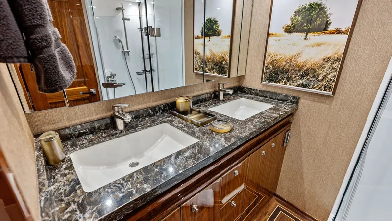 Slide: The Image of Elegant Dual Vanity Bathroom This refined bathroom aboard the 2017 Viking 80 Convertible features a luxurious dual vanity with a striking marble countertop. The rich wood cabinetry and modern fixtures add sophistication and functionality. Large mirrors and tasteful artwork enhance th - 7932666