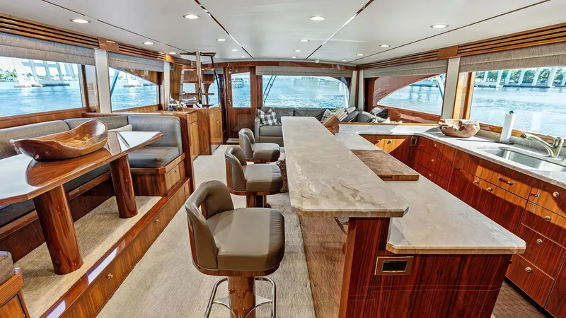 Slide: The Image of Spacious Salon with Bar Seating The salon of the 2017 Viking 80 Convertible 'Aussie Rules' offers a luxurious and inviting space featuring plush bar seating and an elegantly designed dining area. High-quality wood finishes and expansive windows provide a warm ambiance with stunning pano - 7932644