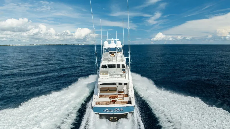 Slide: The Image of Aerial View of Aft Deck and Wake This striking aerial shot captures the commanding presence of the 2017 Viking 80 Convertible, 'Aussie Rules,' as it elegantly cuts through the water. The expansive aft deck is visible, showcasing a spacious seating area perfect for entertainment and relax - 7932729