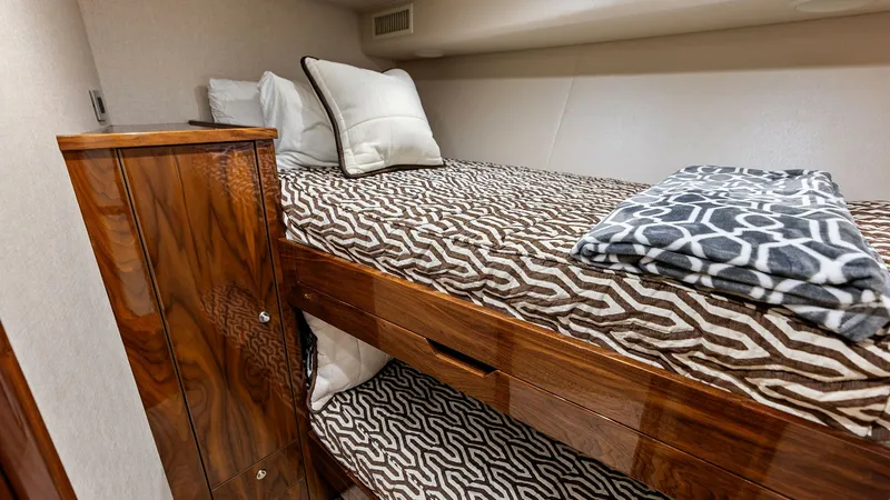 Slide: The Image of Guest Stateroom with Bunk Beds This cozy guest stateroom features elegant bunk beds with patterned bedding, providing comfort and style. The rich wood cabinetry offers ample storage, complemented by soft lighting that creates a warm and inviting atmosphere. Ideal for accommodating gues - 7932671
