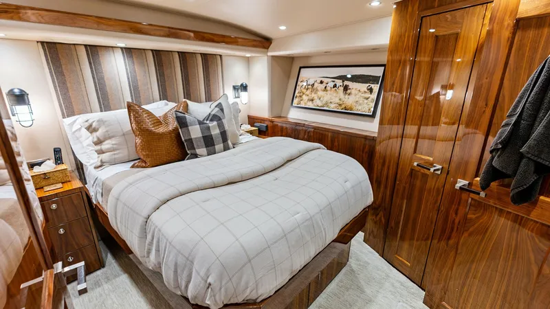 Slide: The Image of Luxurious Master Stateroom Interior The master stateroom of the 2017 Viking 80 Convertible exudes elegance with its rich wood finishes and plush bedding. Ambient lighting and stylish wall sconces enhance the warm, inviting atmosphere. The room features ample storage and a sophisticated desi - 7932668