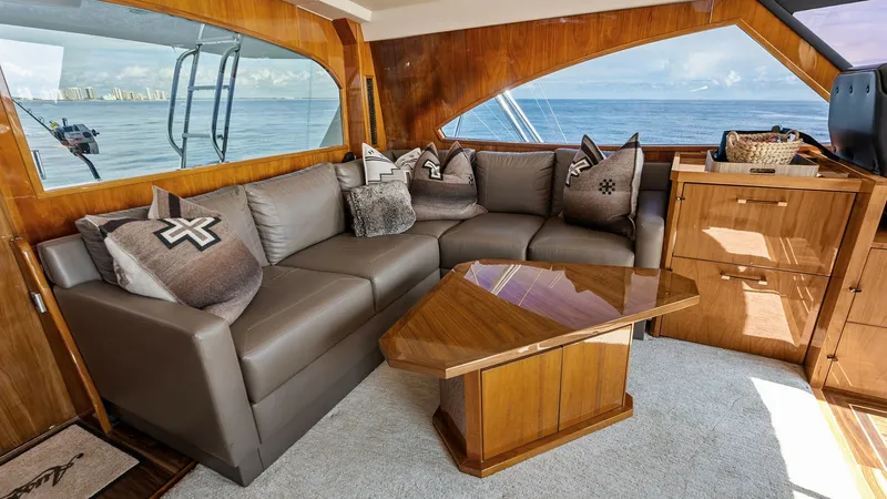 Slide: The Image of Luxurious Salon Seating Area The salon of the 2017 Viking 80 Convertible features a plush L-shaped sofa adorned with elegant cushions, offering comfort and style. Rich wood finishes and large windows create an inviting atmosphere with panoramic ocean views. The sophisticated coffee t - 7932684