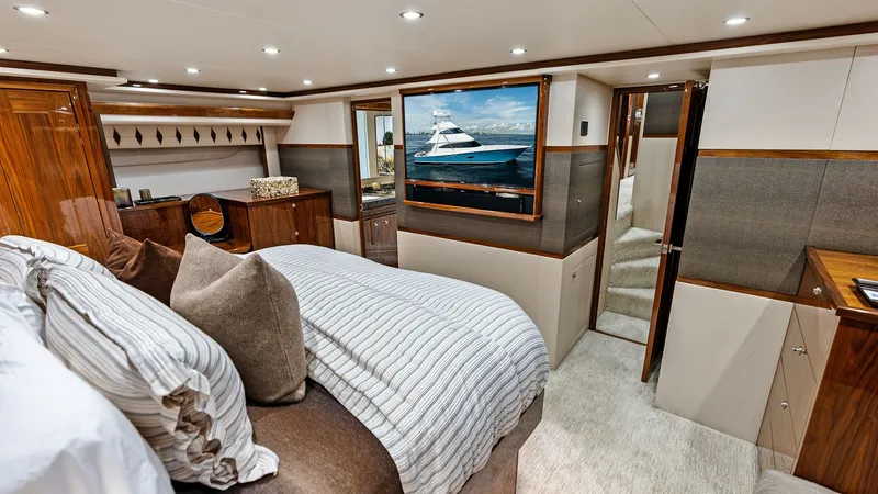Slide: The Image of Luxurious Master Stateroom This elegant master stateroom on the 2017 Viking 80 Convertible showcases a plush queen-sized bed with high-quality linens and ample pillows. The room features rich wood finishes, a large flat-screen TV, and ample storage, creating a warm and inviting spa - 7932664