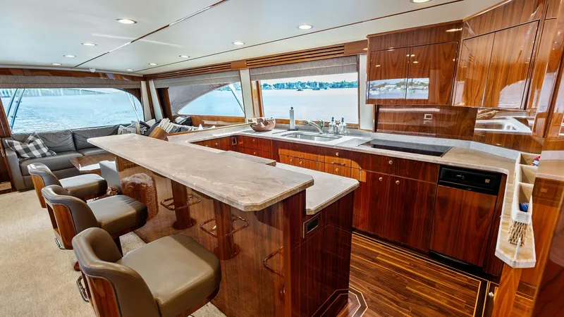 Slide: The Image of Spacious Galley and Lounge Area The interior of the Viking 80 Convertible showcases a luxurious galley with rich wood cabinetry and elegant countertops. The open-plan design flows seamlessly into a comfortable lounge area, featuring plush seating with expansive windows offering stunning - 7932653