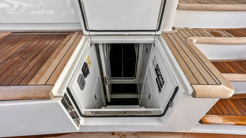 Slide: The Image of Engine Room Access Hatch This image showcases the engine room access hatch on the Viking 80 Convertible, highlighting the precision craftsmanship of its teak decking. The hatch is designed for easy access, ensuring both functionality and style. The surrounding area features metic - 7932702