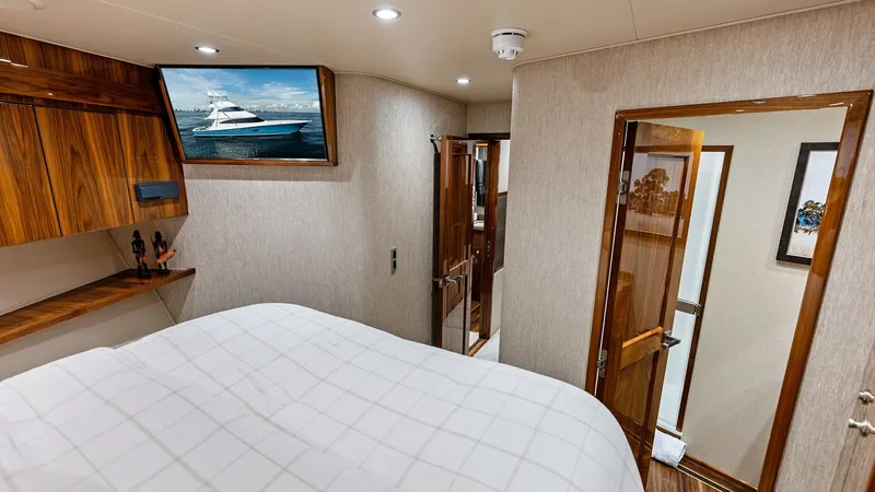 Slide: The Image of Guest Stateroom with Ensuite Access This inviting guest stateroom on the 2017 Viking 80 Convertible 'Aussie Rules' features elegant wood finishes and comfortable bedding. The room is equipped with a flat-screen TV and ample storage, ensuring a cozy stay. Direct access to a private ensuite b - 7932678