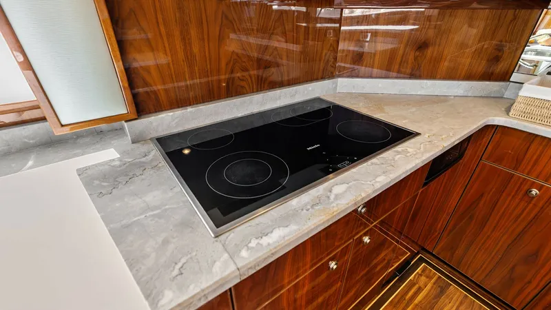Slide: The Image of Galley with Modern Induction Cooktop The galley of the 2017 Viking 80 Convertible features a sleek induction cooktop set into a polished gray countertop, offering both style and functionality. Rich wood cabinetry complements the modern design, providing ample storage space. The high-gloss fi - 7932655