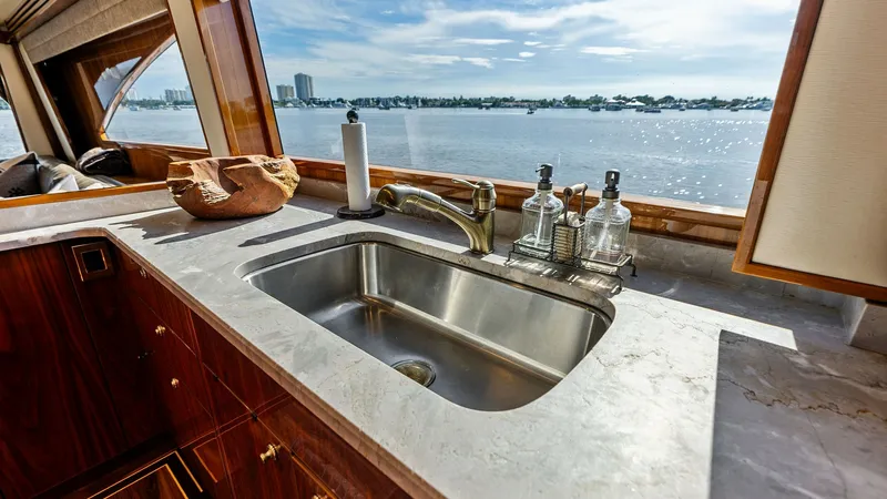 Slide: The Image of Galley Sink with Ocean View This elegant galley features a polished stainless steel sink set in a luxurious marble countertop. The expansive windows provide stunning panoramic views of the ocean, enhancing the open and airy feel of the space. Rich wooden cabinetry adds warmth and so - 7932654