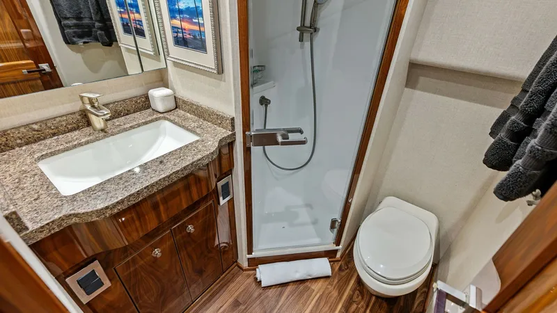 Slide: The Image of Elegant Ensuite Bathroom with Shower This sophisticated ensuite bathroom on the Viking 80 Convertible features a sleek, glass-enclosed shower and a modern vanity with polished granite countertops. The rich wood cabinetry and flooring add a touch of luxury, while the tasteful decor, including - 7932676