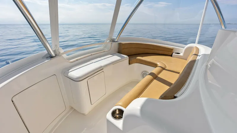 Slide: The Image of Flybridge Seating Area with Ocean View This inviting flybridge seating area on the 2017 Viking 80 Convertible offers a stunning panoramic view of the ocean. The plush, L-shaped tan upholstery provides comfortable lounging, perfect for relaxation or socializing. The sleek, white fiberglass fini - 7932690