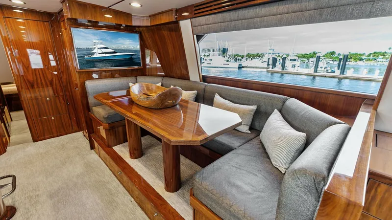 Slide: The Image of Elegant Salon with Panoramic Views The salon of the Viking 80 Convertible boasts a luxurious and spacious seating area with plush, L-shaped sofas around a beautifully crafted wooden table. Large windows provide panoramic views and an abundance of natural light, enhancing the warm, inviting - 7932658