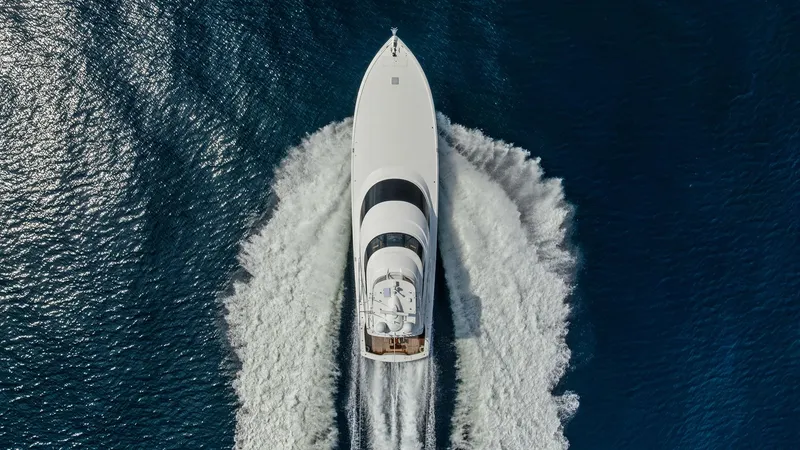 Slide: The Image of Aerial View of Yacht in Motion This striking aerial shot captures the Viking 80 Convertible slicing through the water with power and grace. The sleek design and expansive deck layout are highlighted, showcasing the yacht's impressive performance and luxurious appeal. The wake pattern e - 7932723