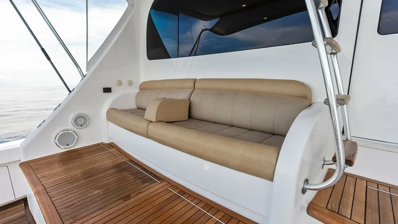 Slide: The Image of Aft Deck Seating Area The aft deck of the 2017 Viking 80 Convertible features a spacious seating area with plush, tan upholstery, providing a comfortable spot for relaxation. The teak flooring adds a touch of elegance, while the seamless integration with the outdoor environmen - 7932701