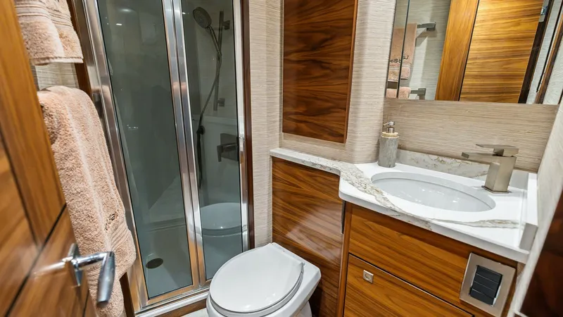 Slide: The Image of Luxurious En-Suite Bathroom This elegant en-suite bathroom on the 2024 Viking 68 Convertible features a modern glass-enclosed shower and a sleek vanity with a polished countertop. The warm wood cabinetry adds a touch of sophistication, complementing the high-end fixtures and ample s - 7933143