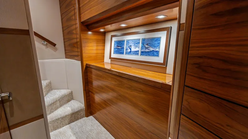 Slide: The Image of Elegant Interior Stairway This image showcases the elegant interior stairway of the 2024 Viking 68 Convertible. The polished wood paneling provides a warm and luxurious ambiance, complemented by soft, recessed lighting. The artwork adds a touch of sophistication, making this passa - 7933132