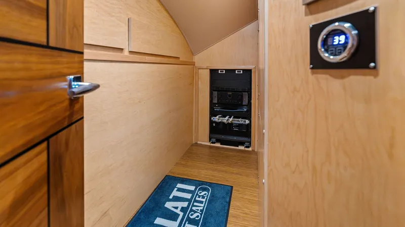 Slide: The Image of Lower Deck Equipment Room This image showcases the equipment room on the lower deck of the 2024 Viking 68 Convertible. The space is efficiently designed with sleek wood paneling and easy access to essential systems. A digital control panel is visible, ensuring seamless operation a - 7933131