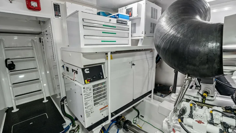 Slide: The Image of Engine Room with Generator Setup This image showcases the meticulously organized engine room of the 2024 Viking 68 Convertible, 'Laid Back'. The space features a robust Cummins Onan generator, ensuring reliable power for all onboard systems. The area is well-lit and efficiently arranged, - 7933153