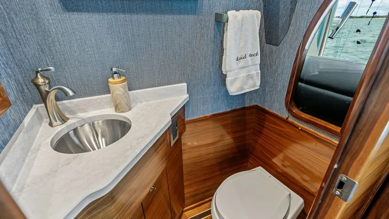 Slide: The Image of Guest Head with Vanity Sink This elegant guest head on the 2024 Viking 68 Convertible features a sleek vanity with a polished metal sink and contemporary fixtures. The rich wooden cabinetry provides ample storage and contrasts beautifully with the smooth, marble-like countertop. A l - 7933124