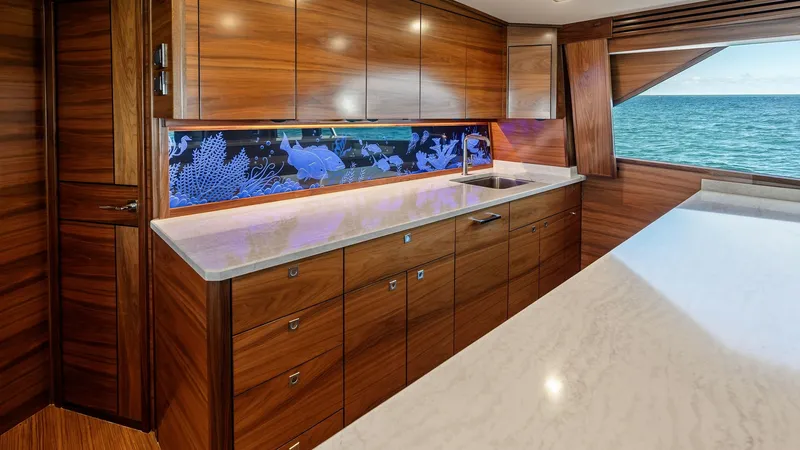 Slide: The Image of Galley with Ocean View This elegant galley on the 2024 Viking 68 Convertible features rich wooden cabinetry and sleek marble countertops. The modern design is complemented by a vibrant backsplash and ample storage space, creating a perfect blend of style and functionality. Larg - 7933128
