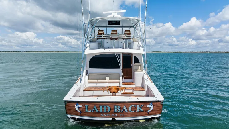Slide: The Image of Aft Deck and Cockpit View The aft deck of the 2024 Viking 68 Convertible, 'Laid Back,' showcases a spacious cockpit designed for both relaxation and fishing. It features a comfortable bench seat, a custom teak table, and ample rod holders, perfect for offshore adventures. The slee - 7933173