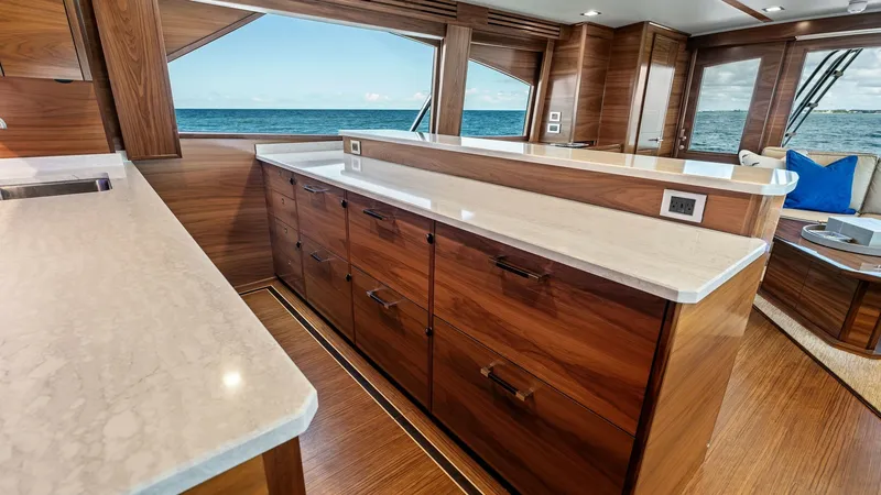 Slide: The Image of Galley with Ocean View This elegant galley on the 2024 Viking 68 Convertible features rich wood cabinetry and sleek countertops, offering both style and functionality. Expansive windows provide stunning ocean views, enhancing the open and airy atmosphere. The layout is designed - 7933129