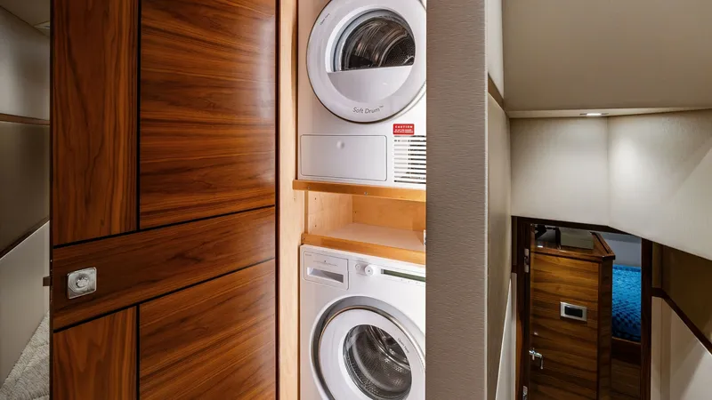 Slide: The Image of Laundry Area with Washer and Dryer This image showcases the convenient laundry area aboard the 2024 Viking 68 Convertible. Featuring a stacked washer and dryer, the space is elegantly integrated with rich wood paneling, providing both functionality and style. The adjacent hallway leads to - 7933133