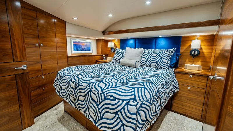 Slide: The Image of Luxurious Master Stateroom Interior The master stateroom of the 2024 Viking 68 Convertible exudes comfort and sophistication with its plush bed adorned with vibrant patterned bedding. Rich wood cabinetry surrounds the space, offering ample storage while adding a touch of elegance. Soft ambi - 7933134