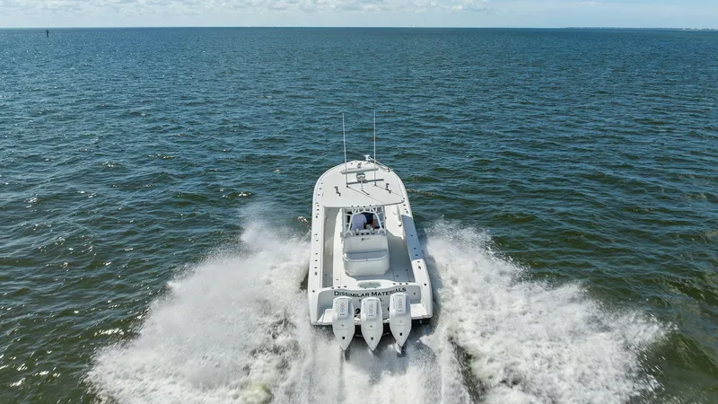 Slide: The Image of Aerial View of Triple Engine Aft This image captures the impressive aft section of the 2014 Yellowfin 39 Center Console, showcasing its powerful triple-engine setup. The boat cuts through the water with ease, demonstrating its superior performance and speed. The expansive deck space is i - 7943355