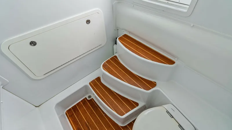 Slide: The Image of Engine Room Access Steps This image showcases the access steps leading to the engine room of the 2014 Yellowfin 39 Center Console. The steps feature elegant teak decking, providing both style and slip-resistant functionality. The bright, white fiberglass finish enhances the clean - 7943343