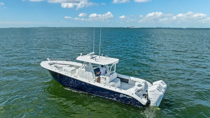 Slide: The Image of Aerial View of Center Console This 2014 Yellowfin 39 Center Console is showcased from an elevated angle, highlighting its sleek design and spacious deck layout. The boat features a robust T-top for shade and twin outboard engines for powerful performance. Its deep blue hull contrasts - 7943348