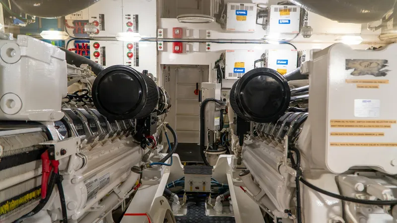 Slide: The Image of Engine Room with Twin Engines The engine room of the 2014 Viking 66 Convertible boasts twin powerful engines, showcasing meticulous engineering and robust design. The space is well-organized, with clearly labeled systems and efficient use of space ensuring easy access for maintenance. - 7943404