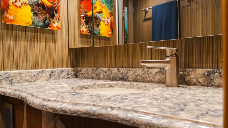Slide: The Image of Elegant Vanity with Marble Countertop This luxurious vanity area features a stunning marble countertop with a sleek, modern faucet, offering both functionality and style. The mirrored cabinetry enhances the sense of space, while the vibrant artwork adds a splash of color and elegance to the s - 7943376