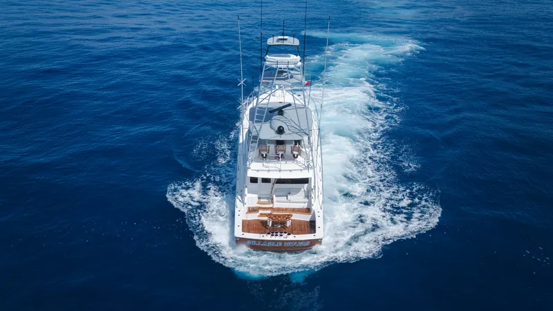 Slide: The Image of Aerial View of Aft Deck in Motion This aerial shot captures the aft deck of the 2014 Viking 66 Convertible, 'Billable Hours,' as it gracefully cuts through the open sea. The teak decking and spacious seating area offer a luxurious and comfortable space for relaxation while cruising. The w - 7943412