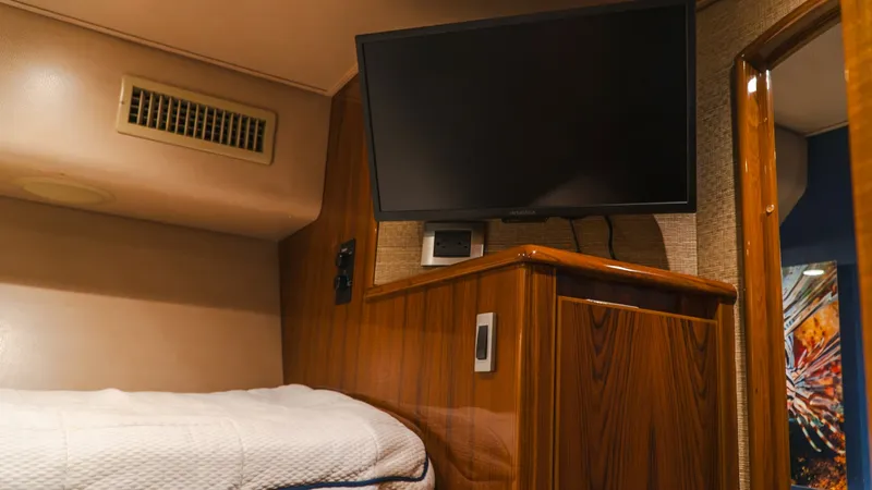Slide: The Image of Guest Stateroom with TV This guest stateroom on the 2014 Viking 66 Convertible features a cozy sleeping area complemented by a wall-mounted flat-screen TV for entertainment. The elegant wood cabinetry and soft ambient lighting enhance the room's warmth and comfort. Ideal for rel - 7943383