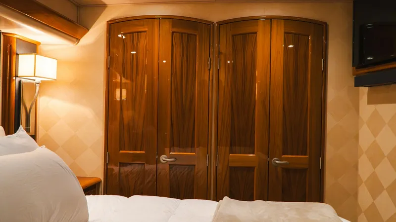 Slide: The Image of Luxurious Stateroom with Wooden Accents This elegant stateroom on the 2014 Viking 66 Convertible features rich wooden cabinetry and soft ambient lighting, creating a warm and inviting atmosphere. The high-gloss finish on the wood enhances the luxurious feel, while the plush bedding promises com - 7943374