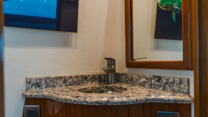 Slide: The Image of Elegant Guest Head Vanity This image showcases the beautifully crafted guest head vanity aboard the 2014 Viking 66 Convertible. The vanity features a stunning granite countertop paired with rich wood cabinetry, providing both elegance and functionality. The modern faucet and large - 7943369